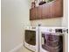 Modern laundry room featuring a washer and dryer with above cabinet storage at 243 Bayou Bend Rd, Groveland, FL 34736