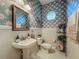 Charming powder room featuring floral wallpaper, pedestal sink, and an octagonal window at 25222 Laurel Valley Rd, Leesburg, FL 34748