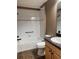 Bathroom features a shower-tub combo, white tiled walls and stone countertop at 2530 Hanlon Ter, The Villages, FL 32162