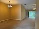 Open-concept living room featuring carpeted floors, sliding glass doors, and a chandelier at 2530 Hanlon Ter, The Villages, FL 32162