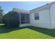 View of the home's rear exterior featuring a screened-in porch and a well-manicured lawn at 2530 Hanlon Ter, The Villages, FL 32162