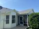 Rear exterior showcasing screened-in porch, an outdoor seating area, and manicured landscaping at 2530 Hanlon Ter, The Villages, FL 32162