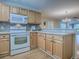 Modern kitchen with wooden cabinets and white appliances that connect to the living area at 2799 Privada Dr, The Villages, FL 32162