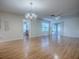 Open-plan living area boasts wood flooring, ceiling fan, chandelier, and views into the bathroom and screened patio at 2799 Privada Dr, The Villages, FL 32162