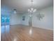 Spacious living room featuring wood floors, neutral walls, chandelier, ceiling fan, and a sliding door to the screened patio at 2799 Privada Dr, The Villages, FL 32162