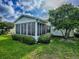 Exterior home view showcasing sunroom addition surrounded by lush landscaping at 2799 Privada Dr, The Villages, FL 32162