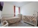 Bright bedroom featuring a crib and daybed, complemented by a neutral palette and soft textures at 29810 Anahid Dr, Leesburg, FL 34748