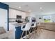 Kitchen island with white cabinetry, stainless appliances, and seating with a living room view at 29810 Anahid Dr, Leesburg, FL 34748