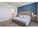 Cozy main bedroom featuring a king-size bed, a blue accent wall, and access to an ensuite bathroom at 29810 Anahid Dr, Leesburg, FL 34748