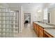 Bathroom with spacious vanity, granite countertop, and glass-blocked window at 3097 Bureau Path, The Villages, FL 32163