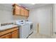 Well-equipped laundry room with sink, wooden cabinets, washer, and dryer for easy convenience at 3097 Bureau Path, The Villages, FL 32163