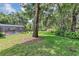 Lush backyard includes a sprawling lawn, mature trees, and a glimpse of the screened-in pool area at 34231 Shadewood Cir, Leesburg, FL 34788