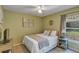 Comfortable bedroom featuring a ceiling fan, window, bedside table and muted green walls at 34231 Shadewood Cir, Leesburg, FL 34788