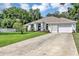 Wide driveway leading to a well-manicured lawn and a charming home with a classic white exterior at 34231 Shadewood Cir, Leesburg, FL 34788