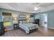 Comfortable main bedroom features a tray ceiling, guitars, three windows, and hard floors at 34231 Shadewood Cir, Leesburg, FL 34788