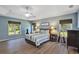 Spacious main bedroom features a tray ceiling, guitars, three windows, and hard floors at 34231 Shadewood Cir, Leesburg, FL 34788