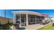 Outdoor living area with a screened-in lanai, fire pit, an umbrella-covered patio set, and well-maintained landscaping at 3466 Smedley Rd, The Villages, FL 32163