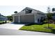 Residential two-car garage with a paved driveway, green lawn, and architectural details at 3466 Smedley Rd, The Villages, FL 32163