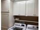 Bright laundry room with front-load washer and dryer and crisp white cabinetry at 3466 Smedley Rd, The Villages, FL 32163