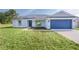 Charming single-story home featuring a blue garage door, grey roof, and nicely landscaped front yard at 472 Malauka Radl, Ocklawaha, FL 32179