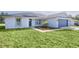 Charming single-story home featuring a blue garage door, grey roof, and nicely landscaped front yard at 472 Malauka Radl, Ocklawaha, FL 32179