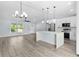 Bright kitchen features stainless appliances, white cabinets and an island that doubles as a breakfast bar with pendant lighting at 472 Malauka Radl, Ocklawaha, FL 32179