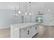 Bright and modern kitchen features an eat-in island, white cabinets, stainless steel appliances, and wood grain floors at 472 Malauka Radl, Ocklawaha, FL 32179