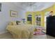 Bright bedroom showcasing a yellow bedspread, bay windows, and colorful accent rug at 4878 Chitty Chatty Run, The Villages, FL 32163