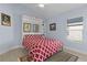 Bright bedroom with built-in shelving, a red and white bedspread, and a window at 4878 Chitty Chatty Run, The Villages, FL 32163