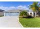 Charming home featuring a three-car garage, light-blue exterior, well-manicured lawn, and decorative driveway at 4878 Chitty Chatty Run, The Villages, FL 32163