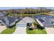 Aerial view of the house featuring a well-manicured lawn, tropical plants, and beautiful lake in the background at 4878 Chitty Chatty Run, The Villages, FL 32163