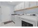 Well-lit laundry room equipped with modern washing machines and ample cabinet space at 4878 Chitty Chatty Run, The Villages, FL 32163
