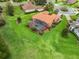 Aerial view of a house with a screened pool and terracotta roof surrounded by a vast green lawn at 5235 Island Terrace Ct, Lady Lake, FL 32159