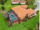 Aerial view of a well-manicured home featuring a screened-in pool and a terracotta tile roof at 5235 Island Terrace Ct, Lady Lake, FL 32159
