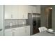 Contemporary kitchen featuring white cabinets, stainless steel refrigerator, and marble backsplash at 5390 Marshelder St, Apopka, FL 32712