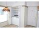 Functional laundry closet with stacked washer and dryer units, built-in shelving, and nearby kitchen at 5436 Astor St, Leesburg, FL 34748