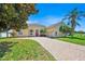 Charming, light yellow home with a brick driveway, red door, and well-maintained landscaping at 5556 Vintage View Blvd, Lakeland, FL 33812