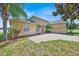 Charming, light yellow home with a brick driveway, red door, and well-maintained landscaping at 5556 Vintage View Blvd, Lakeland, FL 33812