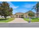 Charming, light yellow home with a brick driveway, red door, and well-maintained landscaping at 5556 Vintage View Blvd, Lakeland, FL 33812