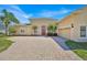 Charming, light yellow home with a brick driveway, red door, and well-maintained landscaping at 5556 Vintage View Blvd, Lakeland, FL 33812