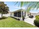 Exterior view of sunroom and patio set in a manicured backyard with mature landscaping, offering a peaceful and private retreat at 579 Audrey Ln, The Villages, FL 32162