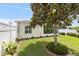 Landscaped backyard featuring a well-maintained lawn, mature tree, and manicured garden beds, creating a serene outdoor oasis at 579 Audrey Ln, The Villages, FL 32162