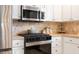 Modern gas stove with stainless steel microwave above and stainless refrigerator to the side at 579 Audrey Ln, The Villages, FL 32162