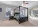 Inviting bedroom featuring a four-poster bed, neutral walls, and a sliding glass door leading to the outdoors at 7350 Spring Mountain Ln, Yalaha, FL 34797