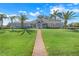 Charming single-story home featuring lush lawn, mature palms, and a welcoming brick pathway at 7350 Spring Mountain Ln, Yalaha, FL 34797