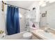 Clean bathroom features a shower-tub combo with blue curtain, tiled walls, and natural lighting at 8850 Se 156Th St, Summerfield, FL 34491