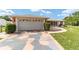 Charming single Gathering home featuring an attached garage, landscaped yard, and colorful patterned driveway at 8850 Se 156Th St, Summerfield, FL 34491