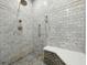Detailed view of a tiled shower with pebble floor, shower bench and handheld sprayer at 9269 Silver Lake Dr, Leesburg, FL 34788