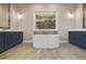 Bathroom featuring a soaking tub, dual vanities with blue cabinets, stylish fixtures, and a modern design at 1042 Sugarloaf Key Loop, Lady Lake, FL 32159