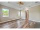 Spacious bedroom with wood flooring, tray ceiling, ceiling fan, and abundant natural light from two windows at 1042 Sugarloaf Key Loop, Lady Lake, FL 32159